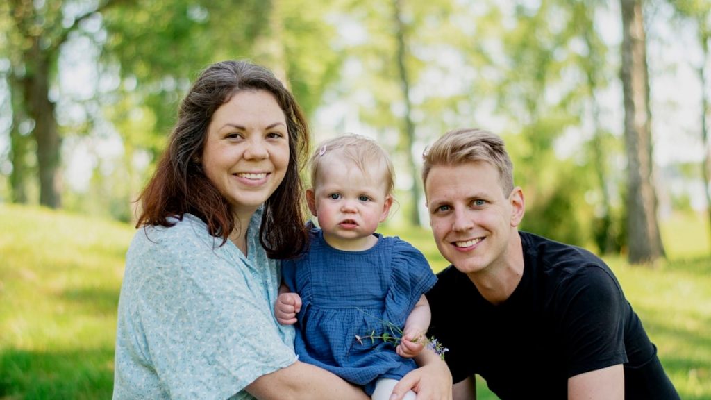 a man woman and child sitting on grass with trees in the background